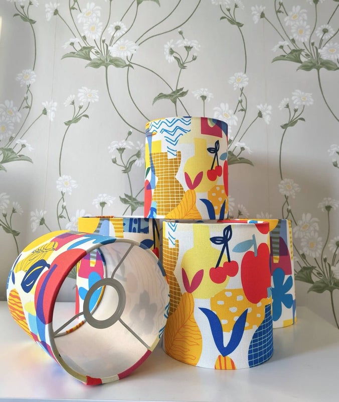 V&auml;rik&auml;s kangasp&auml;&auml;llysteinen lampunvarjostin, jossa graafinen ja leikkis&auml; kuviointi; jokainen varjostin on yksil&ouml;llinen ja kuvio poikkeaa hieman kappaleittain